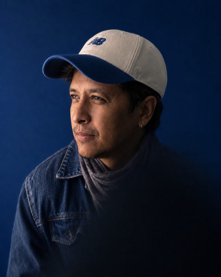 Portrait of Sandy Galabada against a deep blue background.
